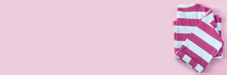 Striped pink T-shirt on paper background. Banner flat lay Top view with copy space for your textの写真素材