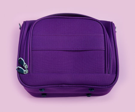 Beautiful textile purple travel bag on pink paper background in zine style. Top view, flat lay, copy...