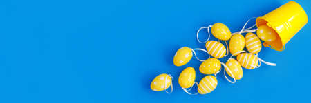 Concept sweet Easter symbols colored yellow eggs and buckets on blue paper background. Flat lay Top view with copy space for your textの写真素材