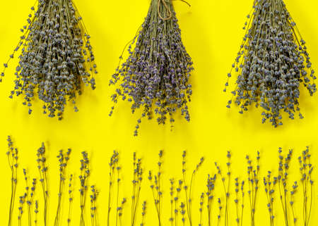 Greeting card with bouquet of dry purple fragrant lavender on yellow paper background. Flat lay, top view, copy space concept.の写真素材