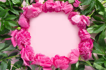 Bouquet of beautiful pink peonies on delicate paper background. Minimal concept backdrop. Template for text. Round frame of flowers. Framed Floral border. Flat lay top view with copy space.の写真素材