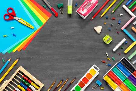 School and office supplies border on black board .. Multicolored pencils, paints, plasticine,...