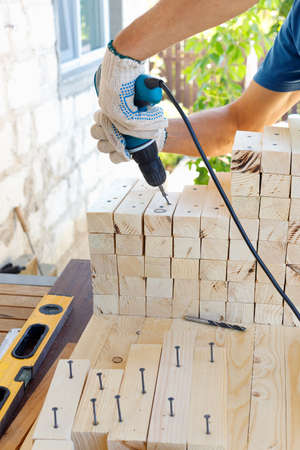 Master cabinetmaker makes wooden furniture with drill, nails, hammer. Handmade in home workshop....