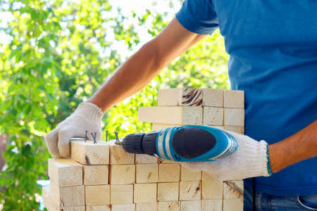 Master cabinetmaker makes wooden furniture with drill, nails, hammer. Handmade in home workshop....