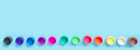 Paints and brushes for painting on blue paper background. Flat lay, top view, copy space concept. Creative web banner.の写真素材