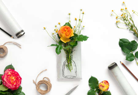 Set of wrapping paper and flowers for handmade on on white background. Homemade craft box gifts with painted vase, bouquet of yellow roses and delicate daisies. Flat lay, top view concept with copy space for text.の写真素材