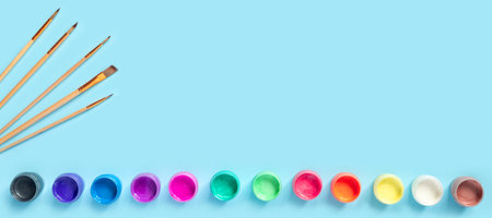 Paints and brushes for painting on blue paper background. Flat lay, top view, copy space concept.の写真素材