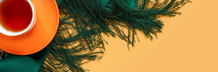 Cup of hot coffee tea with green woolen scarf and autumn foliage on blue paper background. Conceptual postcard for holiday. Flat lay, top view creative with copy space for text.の写真素材