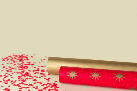 Rolls of gold and red wrapping paper for gifts on beige abstract background. Christmas creative surprise. Copy space for text.の写真素材