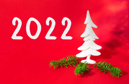 New year holiday card with green fir tree and text 2022 on red paper background. Creative party...
