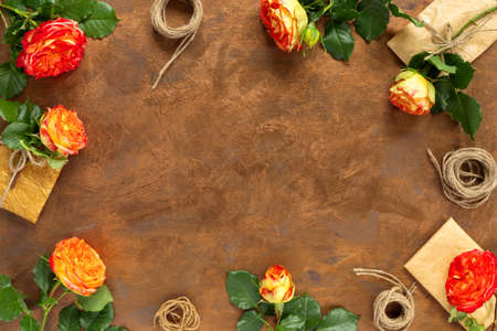 Gifts in paper wrapping, set of vintage yellow package paper, rolls, ropes and pencils for decoration. Bouquet of yellow roses on gold vintage background. Flat lay, top view concept with copy space.の写真素材