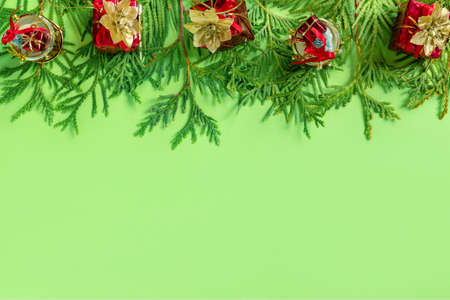 Red gift boxes with gold braid and branches of New Year tree on green paper. Creative christmas...