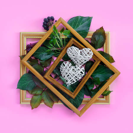 Beautiful white roses with green foliage and hearts in vintage wooden frame on bright pink wall for Valentine's Day. creative greeting card. Copy space for your text.の写真素材