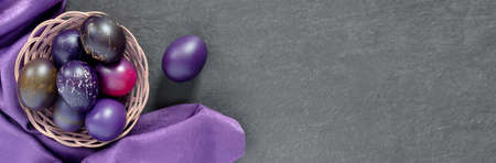 Black nest with painted eggs with silk. Festive Easter banner with branches. concept design. Flat lay top view with copy space.の写真素材