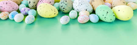 Beautiful Easter banner with colorful eggs on paper green background. Flat lay, top view, copy space...
