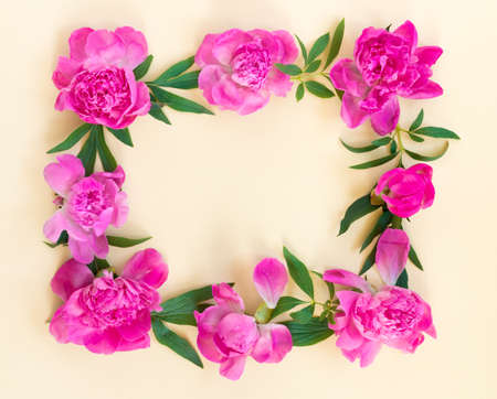 Garland of beautiful pink peonies on yellow paper background with postcard for congratulations or invitations. Creative floral wreath. greeting card for holiday. Flat lay, top view concept with copy space for text.の写真素材
