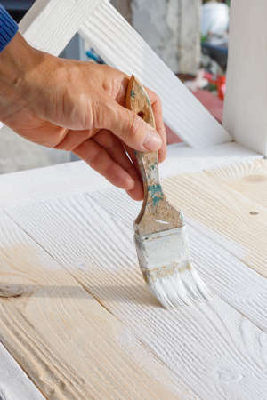 Worker painting white wooden furniture outdoor. Hand with brush close upの写真素材