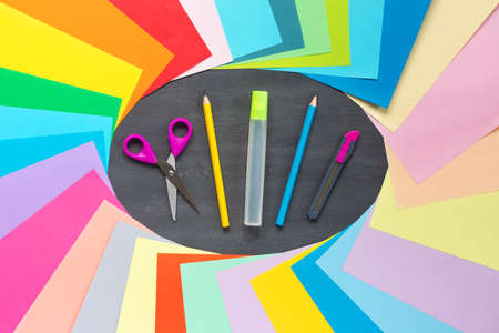 Set of colored paper for schoolwork on background of school board with glue, scissors, pencil. Flat lay, top view for text. Banner.の写真素材