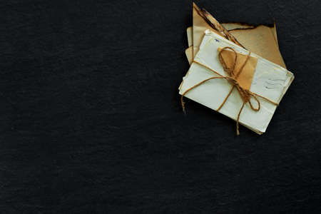 Stack of old torn vintage letters on yellowed paper against black granite table. Vintage concept...