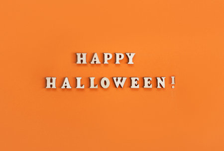 Halloween card on orange background. Banner for congratulations or invitation. Flat lay, top view with text "Happy Halloween!" from wooden letters.の写真素材