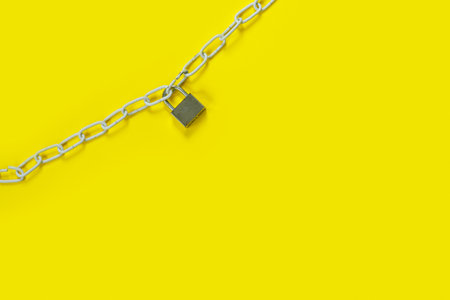 The padlock and chains on yellow background. Flat lay, top view with copy space for text. Banner.