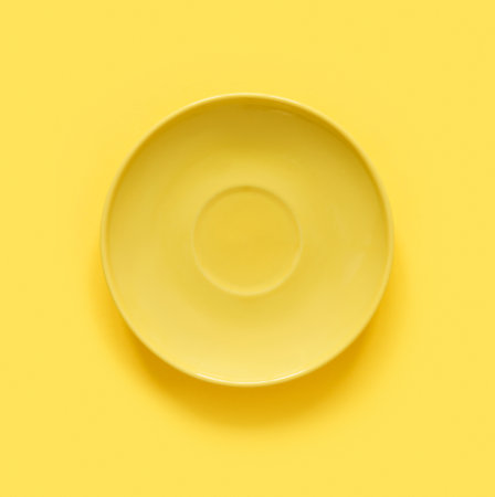 Yellow plates on yellow table. Monochrome minimalistic image in hipster style. Flat lay, top view, copy space for text. creative background.の写真素材