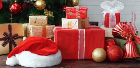 Gift boxes with beads, toys and Santa Claus hat on vintage wooden table in Christmasの写真素材