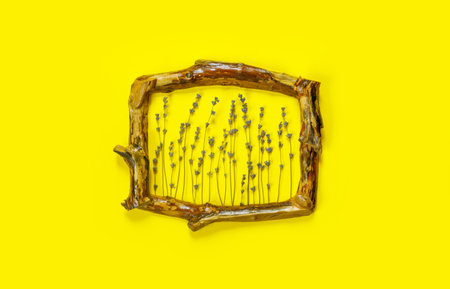 Wooden frames with bouquet of fragrant lavender in rustic style on yellow wall. Holiday party...