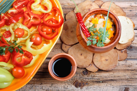 Traditional rustic home vegetable stew with vegetables, spices in clay pots with red wine on old vintage wooden table.Top view flat lay group objectsの写真素材