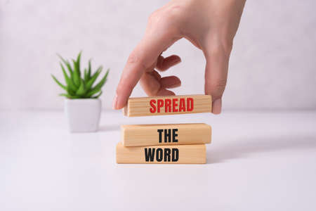 Spread thw word, a word written on a wooden block. Spread the word text on the table, concept.