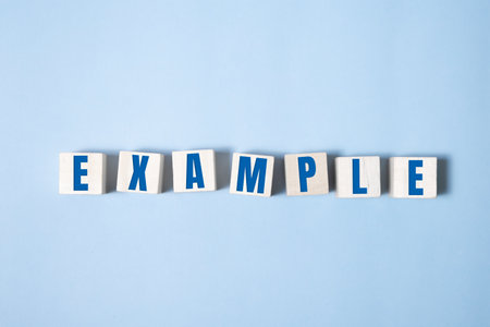 EXAMPLES word made with building blocks on blue background.の素材