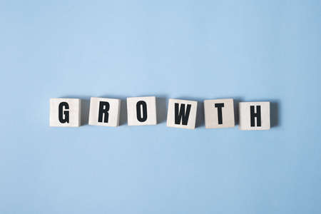 Symbol of growth. a wooden cube and changes words growth. Beautiful blue and white background, copy space. Business and 2021 new year growth concept.の写真素材