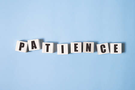 PATIENCE word made with building blocks on blue backgroundの写真素材