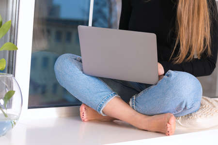 Female copywriter at her workplace, home, writing new text using laptop and Wi-Fi internet connection in the morning.の写真素材
