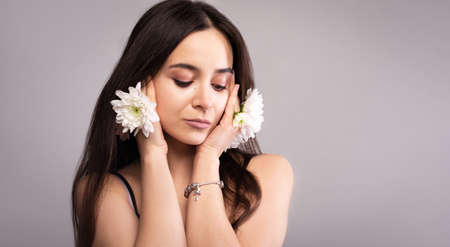 Portrait of a beautiful natural natural blue-eyed girl with white flowers in the wild. Nude make-up.