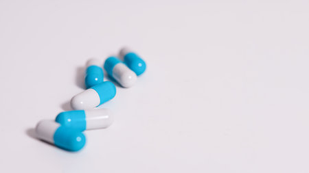 Scattered white pills on blue table. Mock up for special offers as advertising, web background or other ideas. Medical, pharmacy and healthcare concept. Copy space. Empty place for text or logo.の写真素材