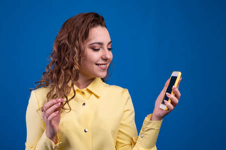 Girl in yellow dress texting on her smartphone. Concept of small text messages and friendly conversation. Mock upの写真素材