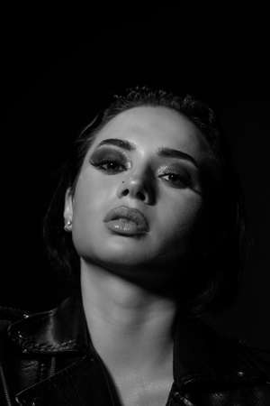 Beautiful stylish woman wearing black leather jacket. Fashionable and self-confident girl with long curly hair. Clothing, style and fashionの写真素材
