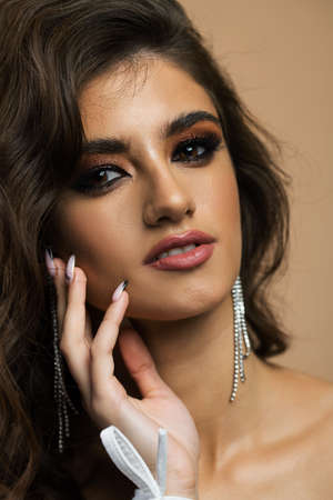 Glamour portrait of beautiful woman model with fresh daily makeup and romantic wavy hairstyle. Fashion shiny highlighter on skin, sexy gloss lips make-up and dark eyebrowsの写真素材