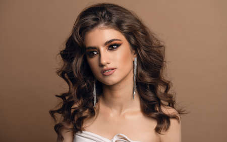 Glamour portrait of beautiful woman model with fresh daily makeup and romantic wavy hairstyle. Fashion shiny highlighter on skin, sexy gloss lips make-up and dark eyebrowsの写真素材