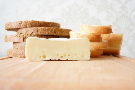 Black and white bread cut by chunks and cheese on a wooden board. Horizontal shootingの写真素材