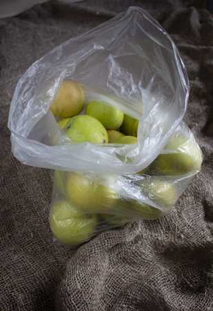 Ripe apples in a plastic bag on burlap clothの写真素材