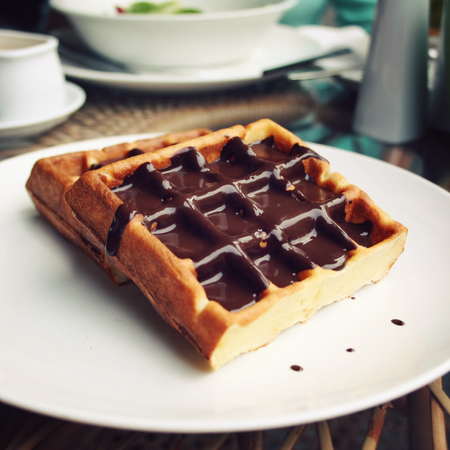 Chocolate covered Vienna Waffles on the white plate. Vintage photo. Viennese Waffles covered with chocolate topping.の写真素材