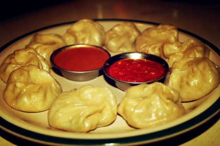 Steamed dumplings with vegetables - vintage effect. Plate of Tibetan Momos with chili sauce - retro...