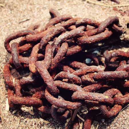 Old rusty anchor chain on the beach of Turkey. Macro. Selective focus. Close up. Twisted into a...