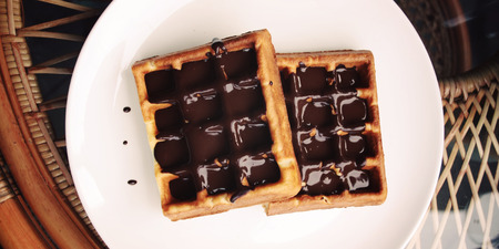 Vienna Waffles. Chocolate topping. Aged. View from the Top. White plate with Chocolate covered Wafers. Toned. Tasty dessert. Wide photo for wallpaper or site slider. Unhealthy but delicious.の写真素材