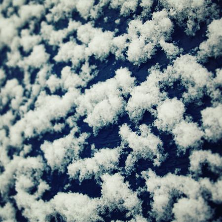 Fluffy snowflakes on the roof. Natural background. Cold winter day. Blue wooden surface covered with snow.の写真素材