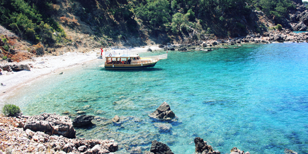 Passenger vessel waiting for tourists. Aged photo. Tourist boat in the small bay. Calm blue sea and green hills in Turkey. Walking the Turkey's Lycian Way. Wide photo for web site slider.の写真素材