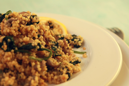 Millet with mushrooms and spinach. Close up. Vegan dish. Vegetarian couscous on the round white plate.の写真素材