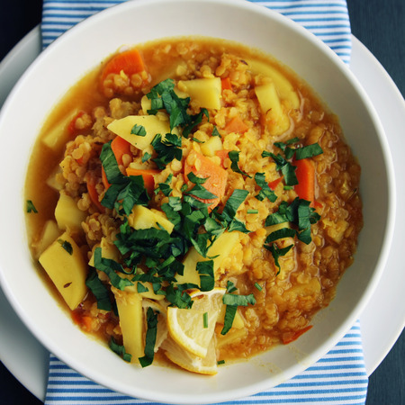 Red lentil stew with potato, carrot and turmeric. Top view. Toned photo. Healthy lunch on the round white plate. Colorful vegan dish with potato, carrot and turmeric. European cuisine. Vegetarian.の写真素材